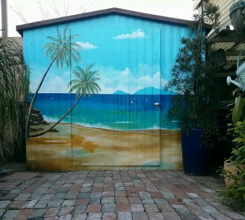 a beach mural painted on the front of a garden shed