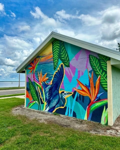 Tropical mural in bold blue and green colors on the back of a shed