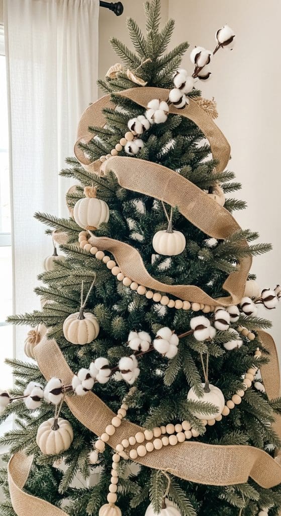 green evergreen tree wrapped in burlap, white pumpkins and cotton stems