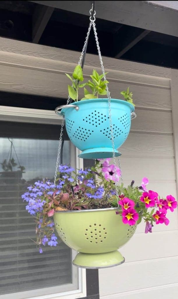 Kitchen colanders being used as hanging planters from porch