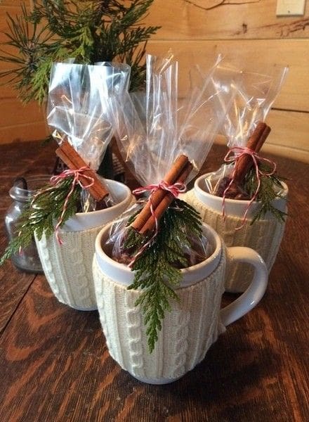 cute mug with a mug cozy, hot chocolate filler and sprigs of cinnamon sticks for a thanksgiving gift basket