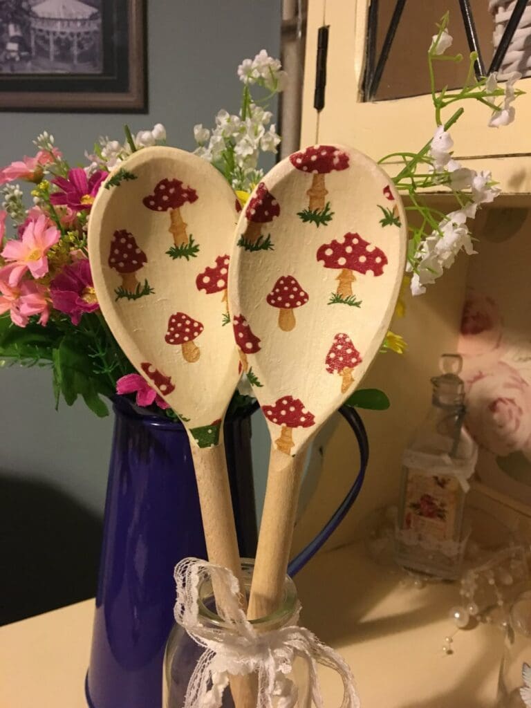 Decorated wooden spoons in a glass jar decorated with red and white mushrooms
