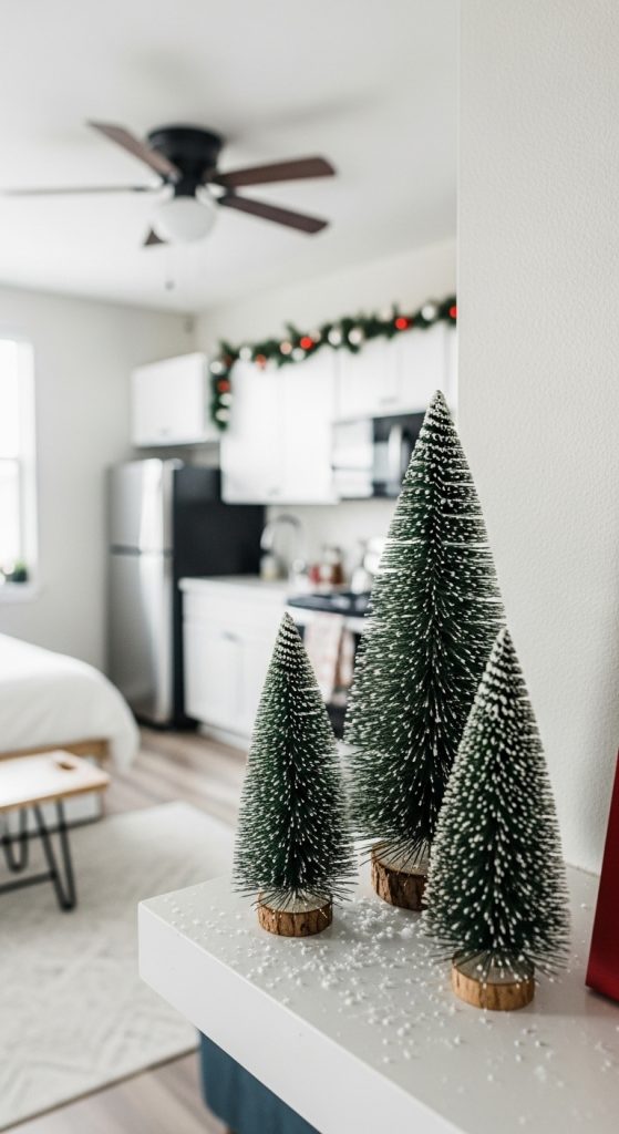 3 mini trees clustered on a shelf with faux snow