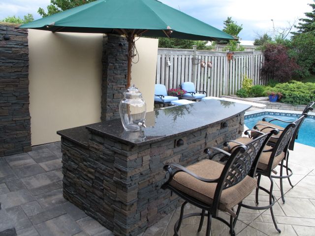 Luxury style bar outdoors by pool made from stone and a granite work top